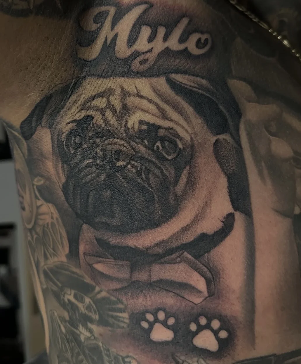 Black & Gray Realism tattoo by EL TAKAS: pug dog, dog paw prints, bow tie, script name