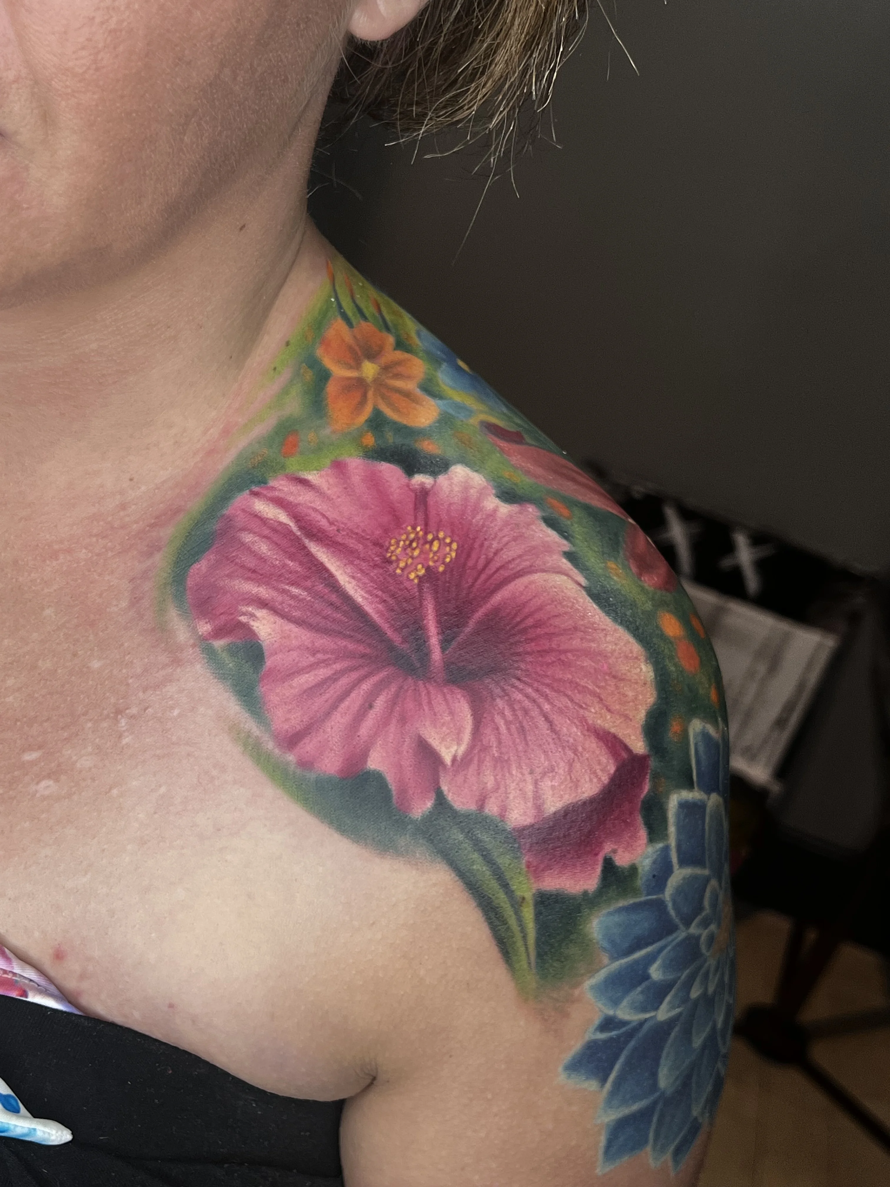 Color Realism tattoo by Joshua Gallant: hibiscus flower, orange flower, green leaves, blue succulent