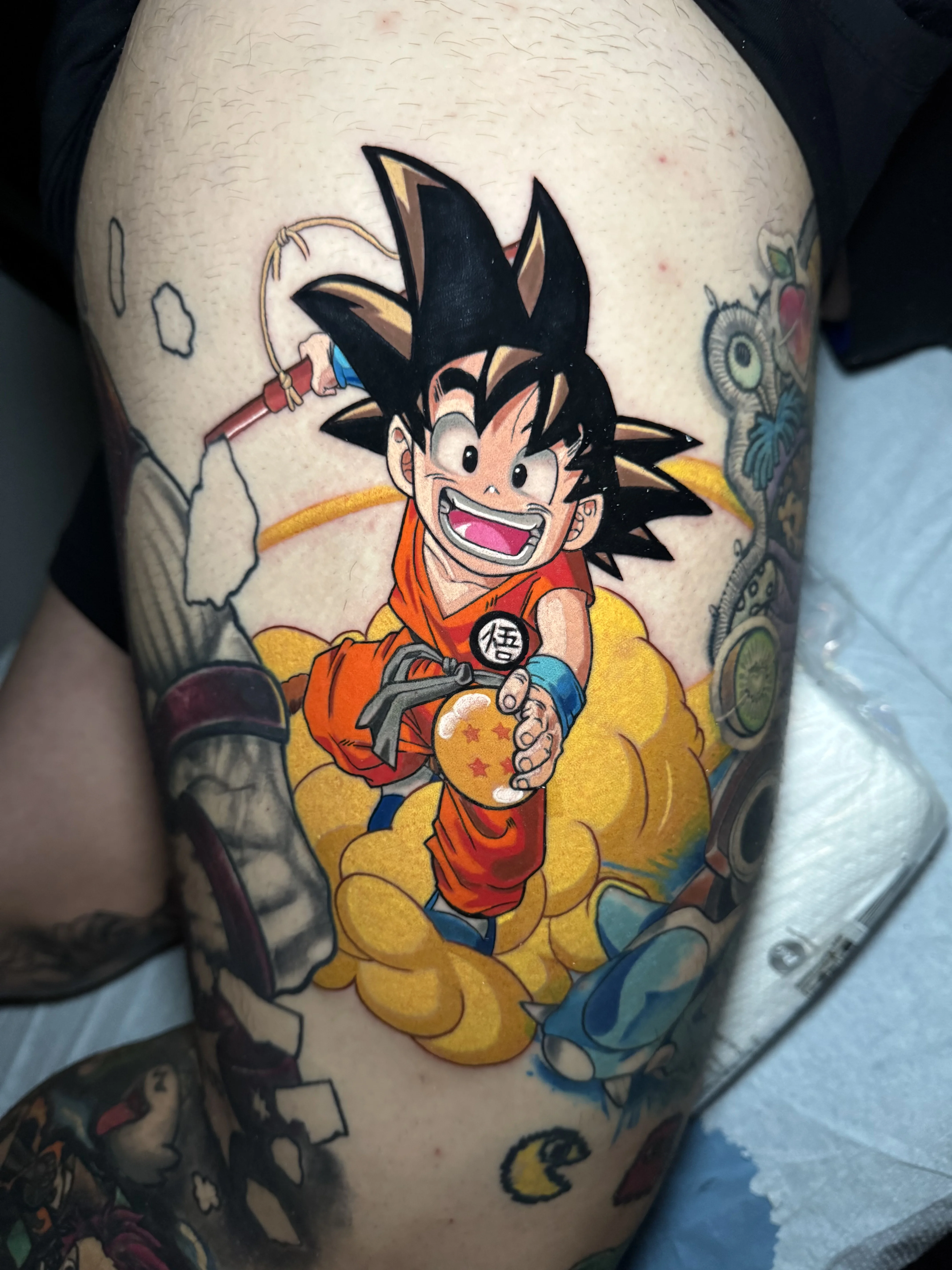 Anime tattoo by Joshua Gallant: young boy, orange martial arts outfit, flying cloud, dragon ball