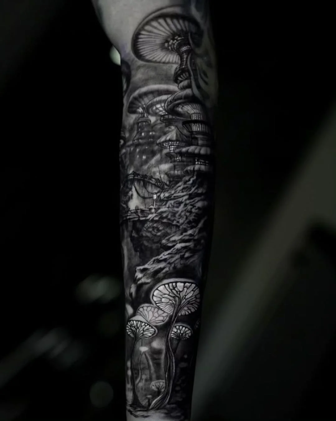 This detailed black and gray piece on the arm depicts surreal glowing mushrooms in a mystical forest, creating a dreamlike fantasy landscape