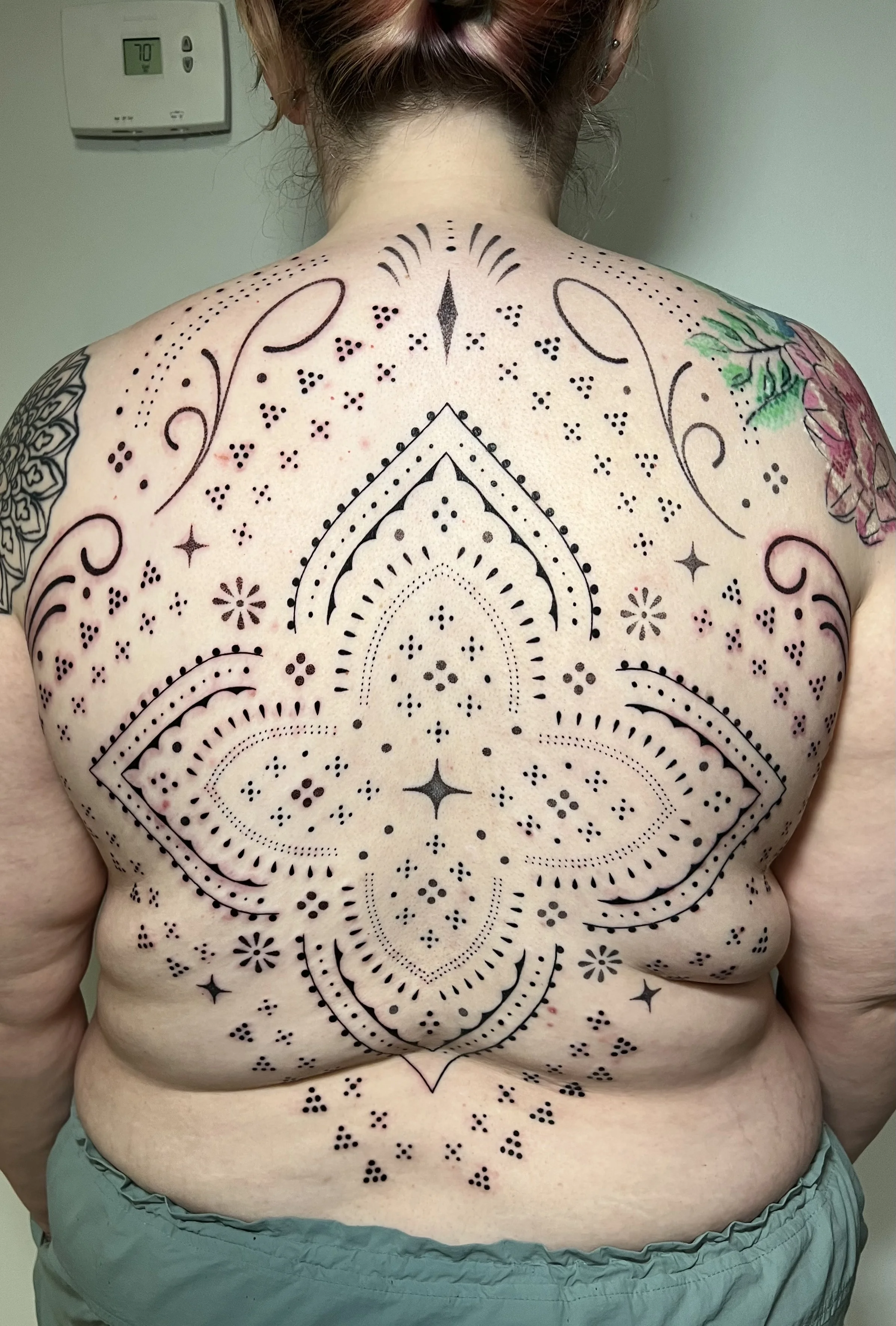 Blackwork tattoo by Erin Manning: decorative dots, floral ornament, curved lines, geometric shapes
