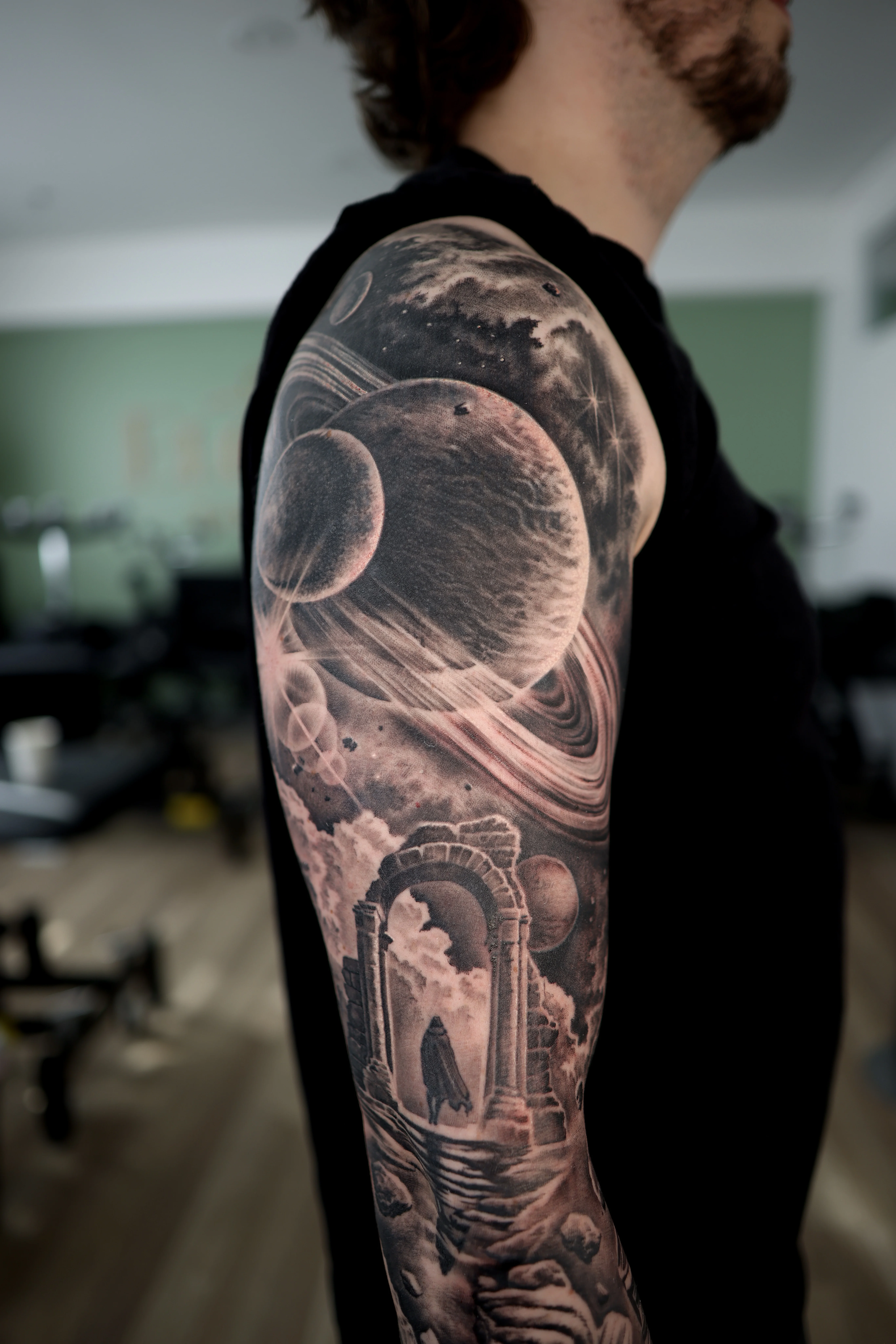 Black & Gray Realism tattoo by Ezra Currier: planet, moon, planet with rings, stone archway