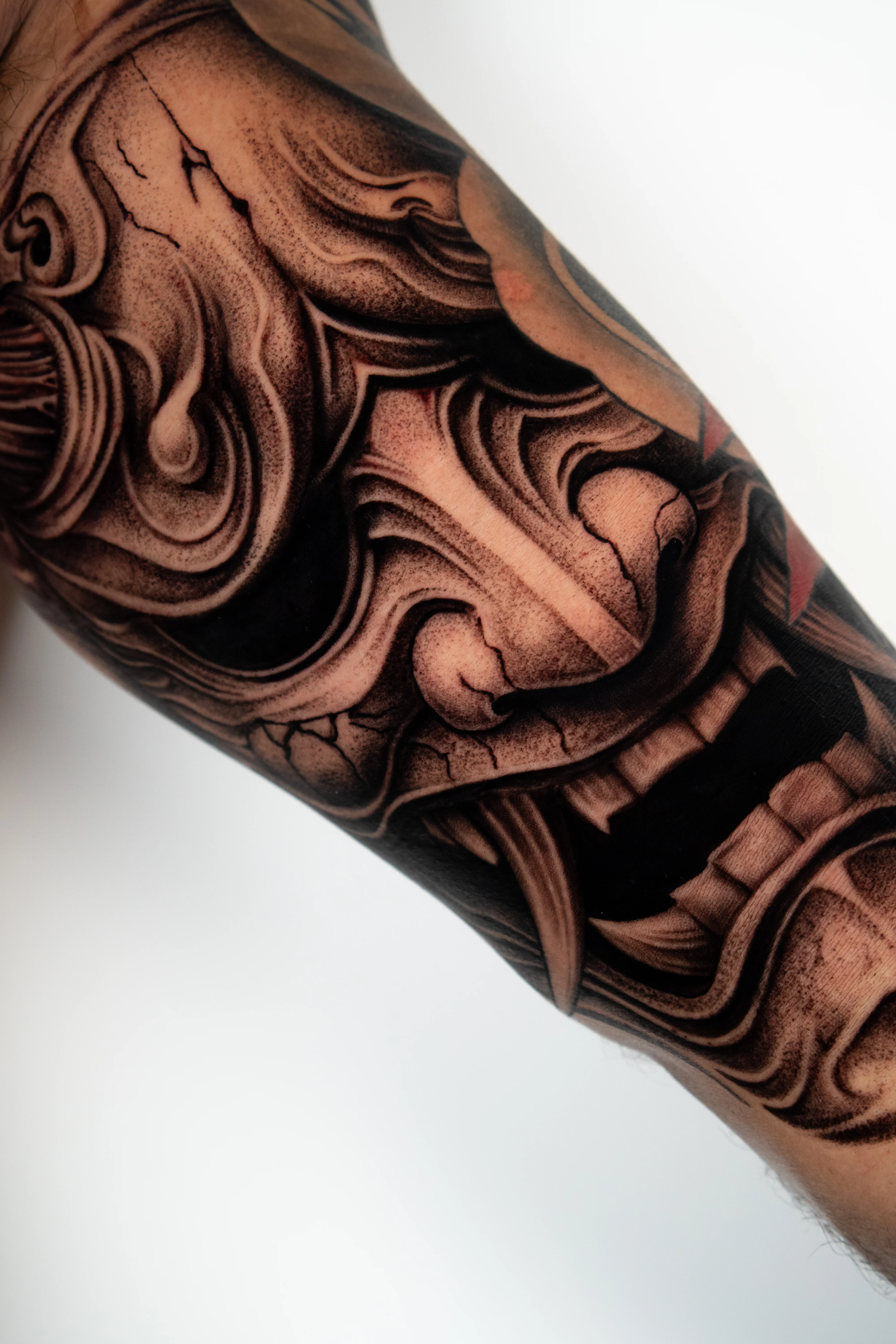 Black & Gray Realism tattoo by Do Santos: demon mask, fanged mouth, crack, mythology