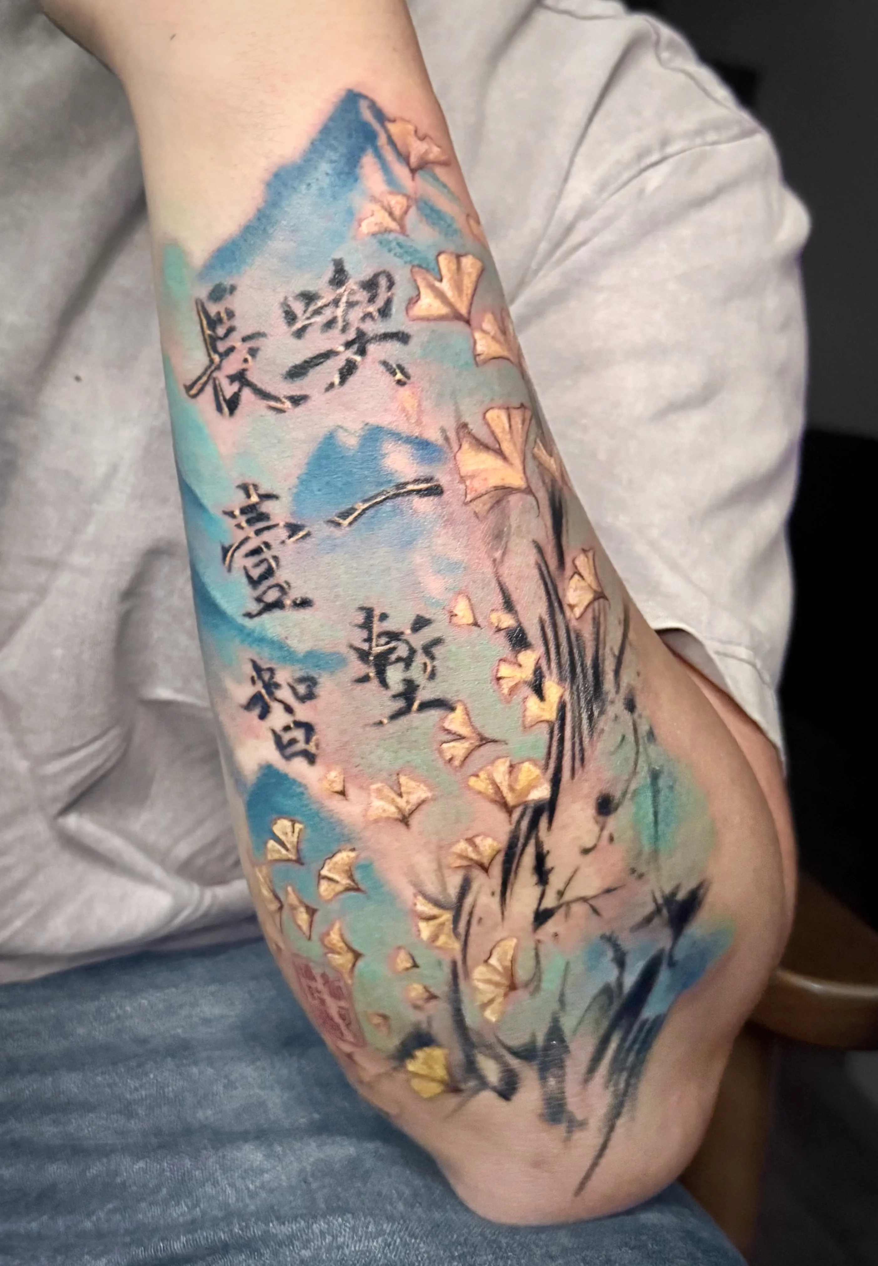 Watercolor tattoo by Nicole Petrou: gingko leaves, abstract shapes, chinese characters, nature