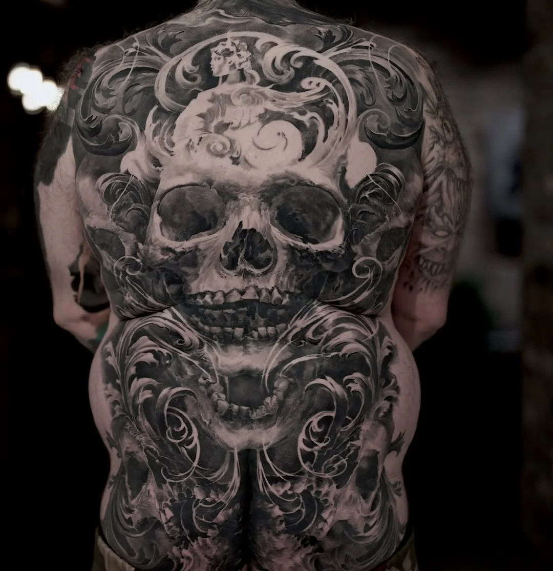 Black & Gray Realism tattoo by Carlos Torres: skull, angel, swirls, filigree