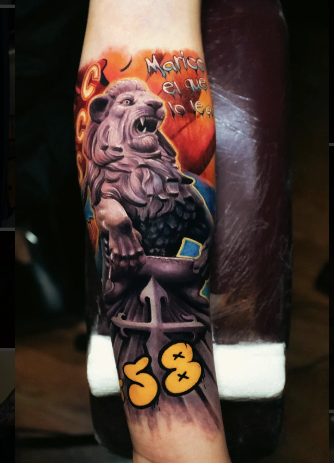 This vibrant forearm piece features a detailed lion statue, colorful background, graffiti-style text and numbers, creating a striking blend