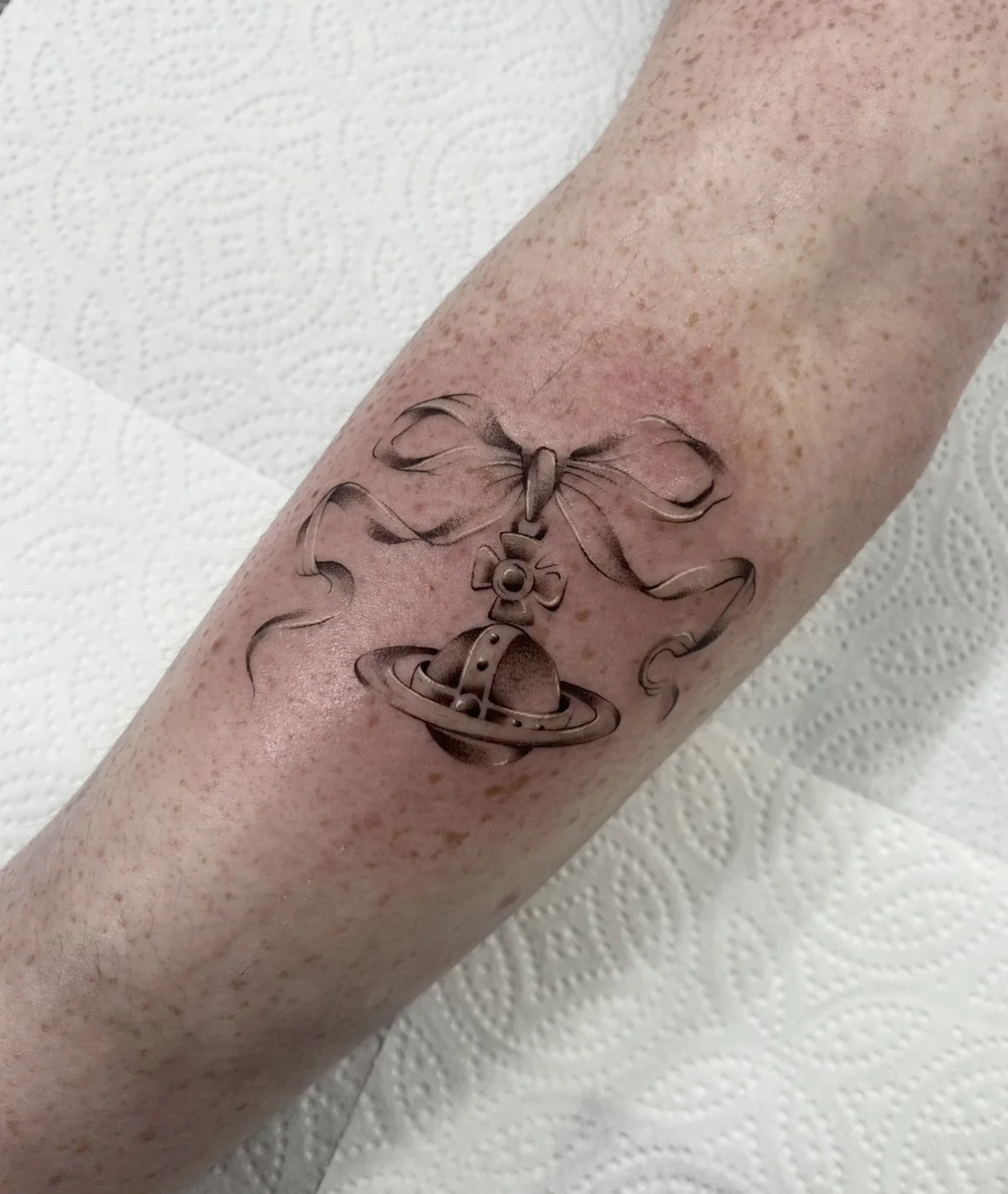 Black & Gray Realism tattoo by Aliye Gaygusuz: planet with rings, bow, ribbon, cross