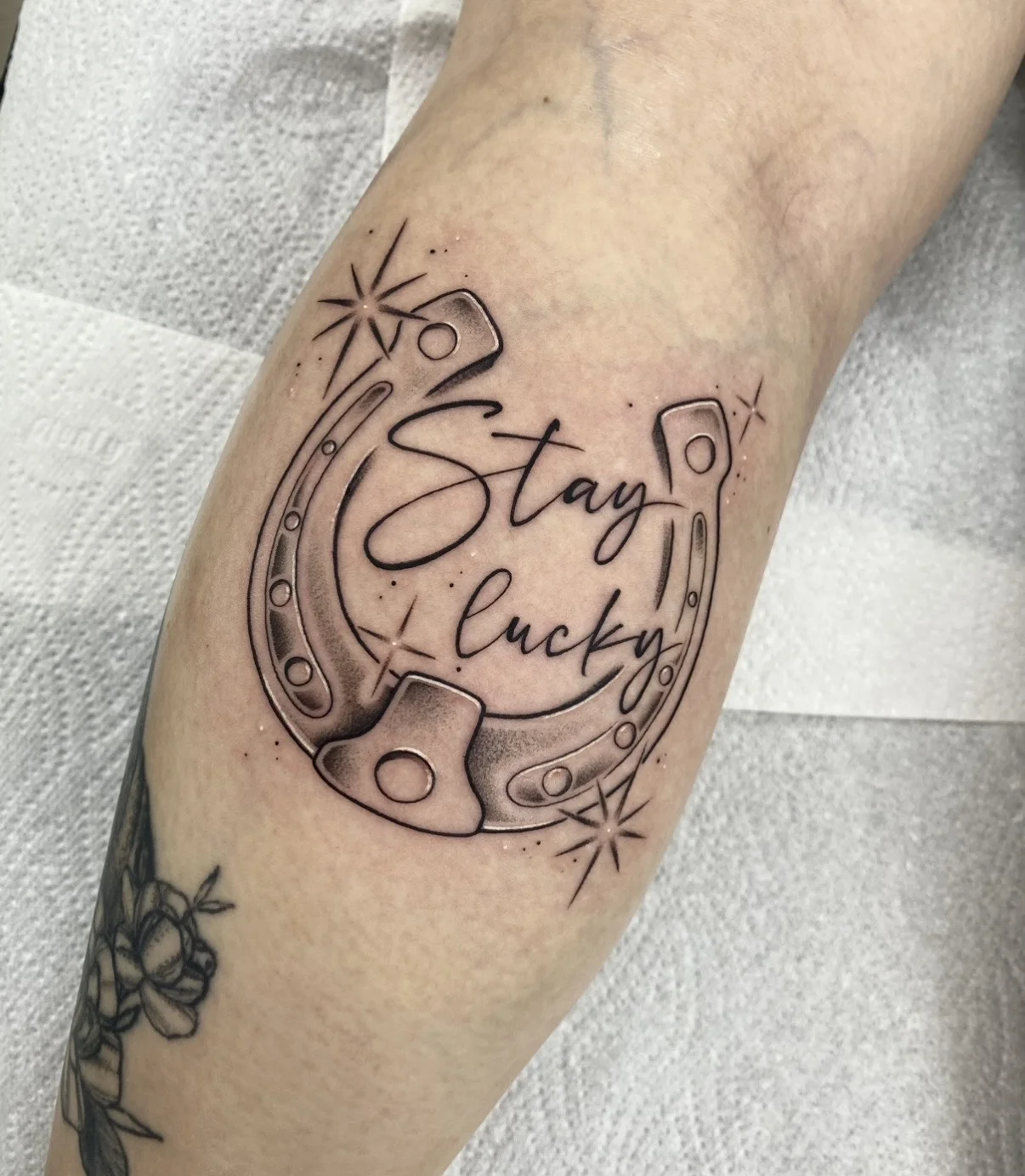 Fine Line tattoo by Aliye Gaygusuz: horseshoe, sparkles, script lettering, luck