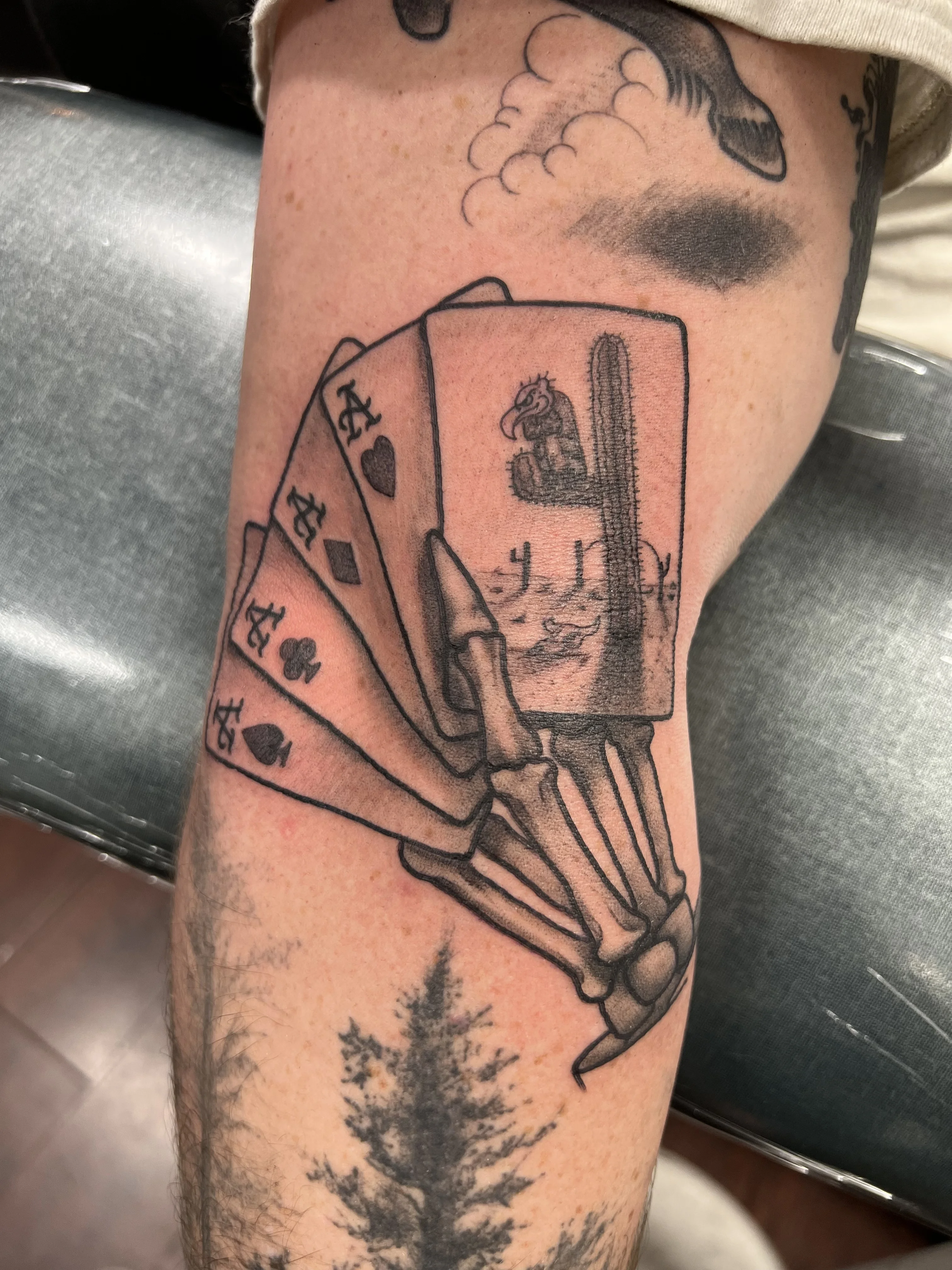 Black & Gray Realism tattoo by Justin Wilson: skeletal hand, playing cards, sparrow, cactus