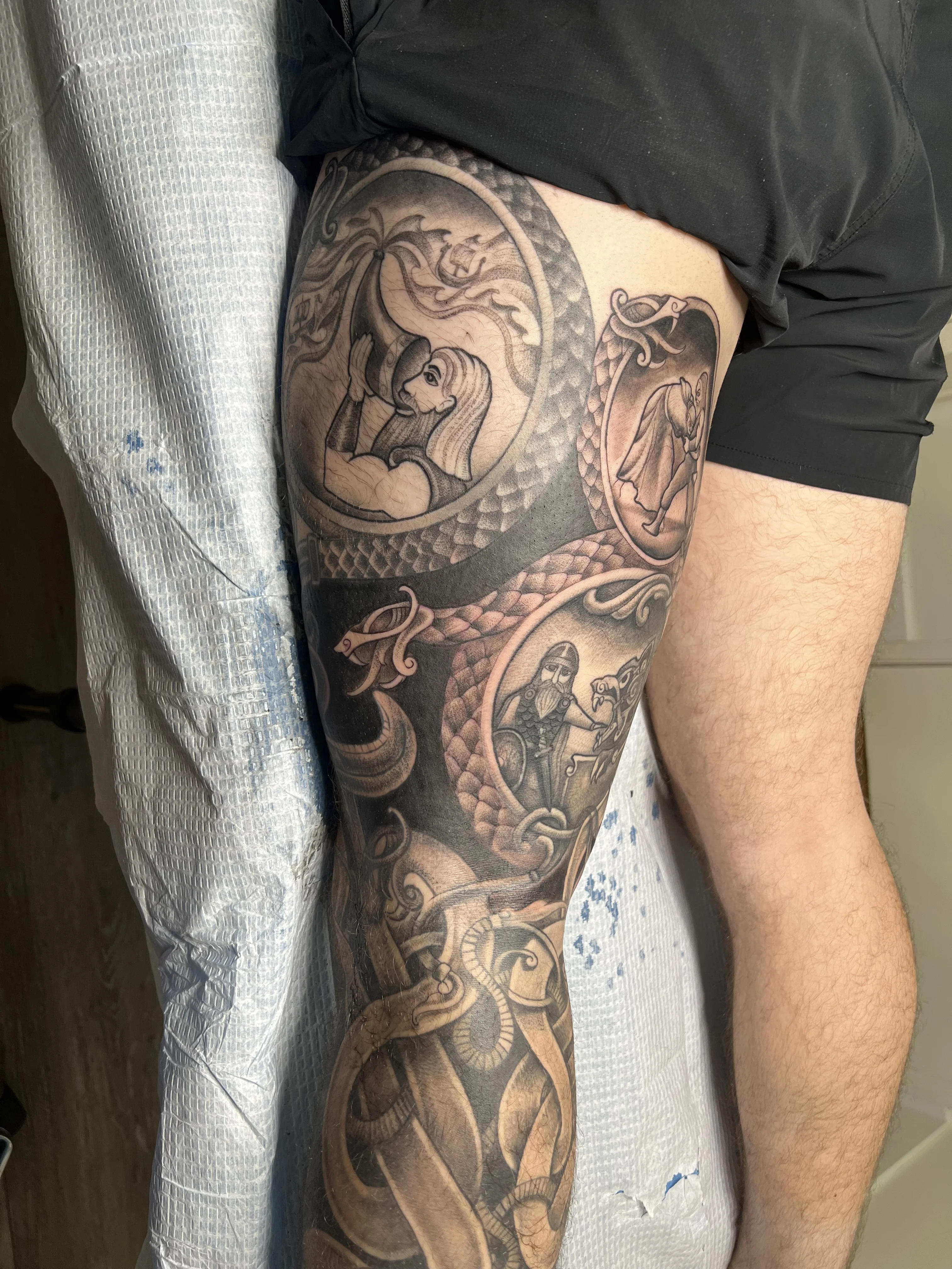 Black & Gray Realism tattoo by Justin Wilson: viking warrior, serpent, bearded man, woman blowing horn