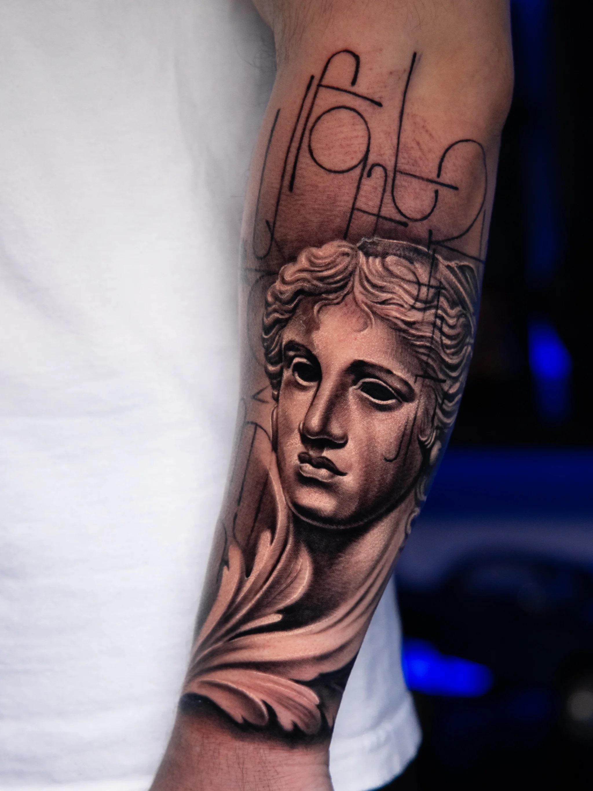 Black & Gray Realism tattoo by T-GRAN Ink: classical sculpture face, facial tear, decorative leaf, mythology